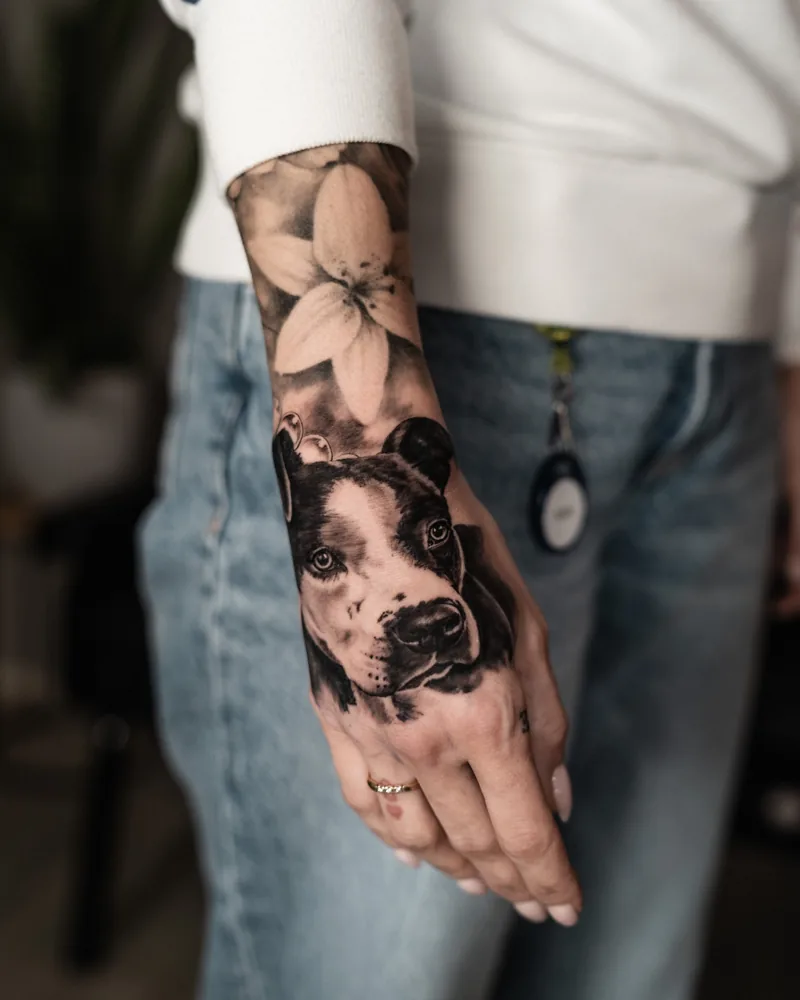 Realistisches Hunde-Tattoo mit Blüten an Unterarm und Hand
