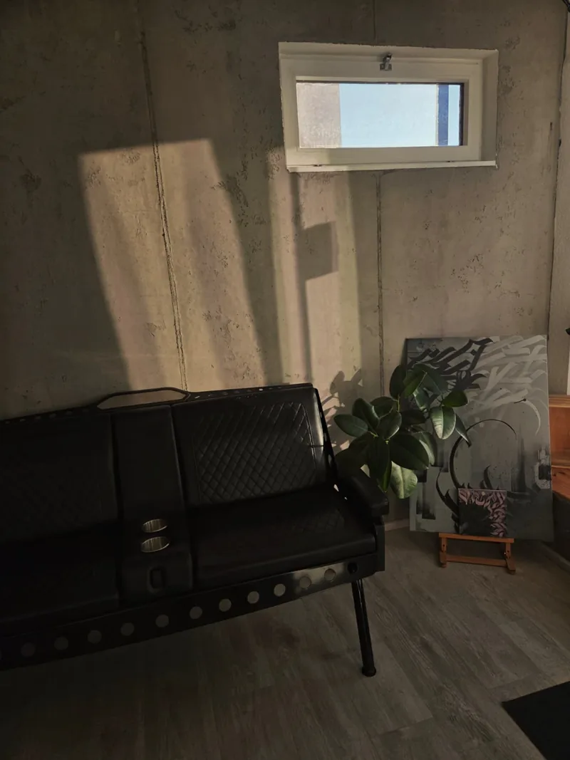 Ledersitzecke mit Betonwand und Pflanzen im Utopia Tattoo Collective